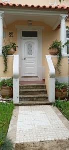 a house with a white door and some plants at Casa da Nogueira in Alvorninha