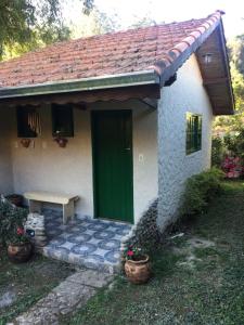 una piccola casa con una porta verde e una panchina di Recanto da Deusa a Bocaina de Minas
