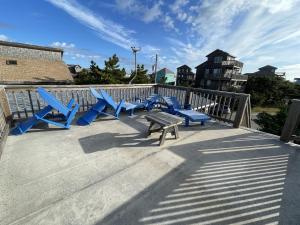 a group of blue chairs and a bench on a deck at CHASING SUNSETS cottage in Hatteras