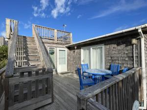 a deck with blue chairs and a table and stairs at CHASING SUNSETS cottage in Hatteras