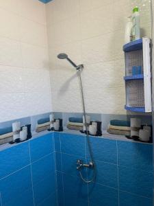a shower in a bathroom with blue tile at VERSE 5 min de la playa in Riffiene