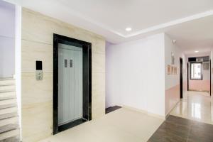 Hotel O PRAMOD PRIME HOMES في Surūrnagar: ممر مع باب في غرفة بجدران بيضاء