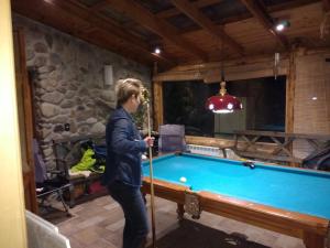 Un hombre con un palo de pie junto a una mesa de billar. en Hospedaje Andorra La Vella, en Ushuaia