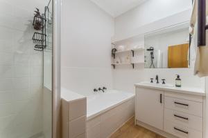 a white bathroom with a tub and a sink and a shower at Cozy Newtown 2 bedroom unit in Geelong