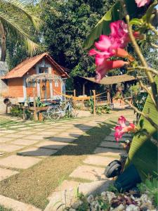 a house in the background with pink flowers in the foreground at Hostel Sossego do Garças in Barra do Garças