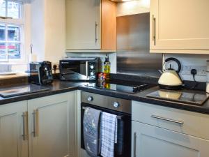 a kitchen with white cabinets and a stove top oven at Staffield Cottage in Kirkoswald