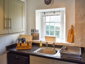 a kitchen counter with a sink and a window at Staffield Cottage in Kirkoswald