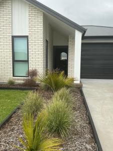 a house with a black garage door and some plants at The Keenans in Whitianga