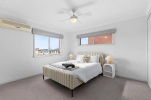 ジーロングにあるThe Geelong Getaway Townhouseの白いベッドルーム(ベッド1台、窓2つ付)