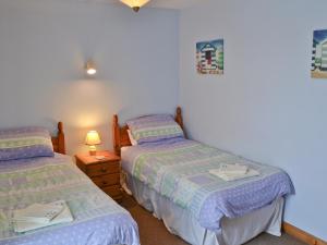 a bedroom with two beds and a night stand with a lamp at Brambles in St. Agnes 