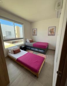 two beds in a room with a window at Paraíso con piscina privada y jacuzzi - Peñaliza in Ricaurte