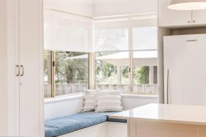 a kitchen with a blue bench in front of a window at Reverie By The Bay - Walk to Beaches, Relax in Style in Dunsborough