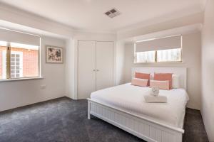 a white bedroom with a large bed with pink pillows at Reverie By The Bay - Walk to Beaches, Relax in Style in Dunsborough