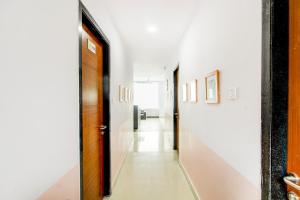 Hotel O PRAMOD PRIME HOMES في Surūrnagar: ممر بجدران بيضاء وباب ولوحات