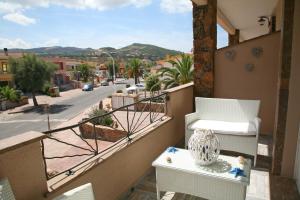 uma varanda com uma cadeira, uma mesa e uma rua em La Rosa Del Mare em Castelsardo