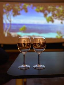 dos copas de vino sentadas en una mesa frente a un televisor en 川平湾から車で10分シアター付きシークレットシーサー, en Ishigaki Island