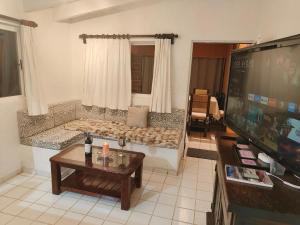a living room with a couch and a flat screen tv at Portal Azahualco Bungalow close to the mountain in Tepoztlán