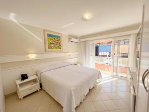 a white bedroom with a bed and a window at Pousada Vila do Coral in Bombinhas +57 photos