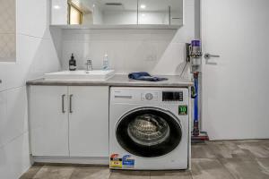 a washing machine in a kitchen with a sink at Beachfront self contained upstairs apartment in Semaphore