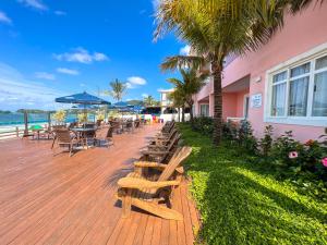 a wooden deck with benches and tables and chairs at Pousada Vila do Coral in Bombinhas