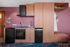 a kitchen with black appliances and a purple wall at George Hotel Launceston, an Ascend Collection Hotel in Launceston