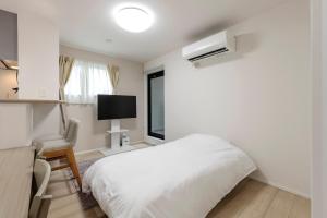 a white bedroom with a bed and a window at Anecis Honjin in Nagoya