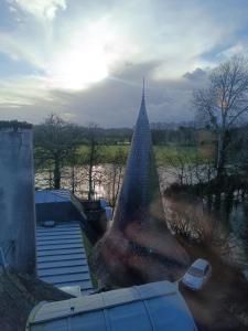 a pyramid building with cars parked next to a river at La Ribaudière Castle in Montauban-de-Bretagne