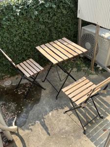 zwei Holzstühle und ein Tisch und zwei Bänke in der Unterkunft サンハウス六本松103 in Susakiuramachi