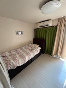 ein kleines Schlafzimmer mit einem Bett in einem Wohnwagen in der Unterkunft サンハウス六本松103 in Susakiuramachi