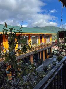 a yellow building with a balcony with a mountain in the background at Alley Homestay SaPa in Sa Pa