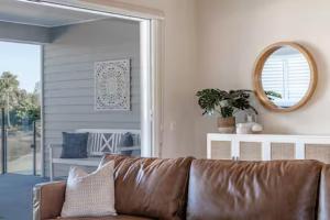 a brown leather couch in a living room with a mirror at Capri Waterfront Resort-Style 5BR & Pool in Gold Coast +41 photos