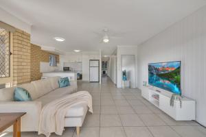 a living room with a couch and a tv on a wall at North Facing 2 Bedroom Apartment at Cotton Tree in Maroochydore