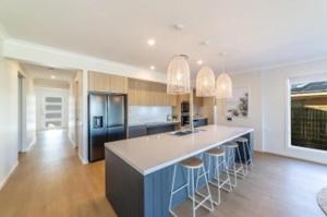 a kitchen with a large island with bar stools at Capri Waterfront Resort-Style 5BR & Pool in Gold Coast