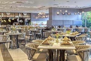 a dining room with tables and chairs in a restaurant at Novotel Rockwell View Hotel Residences in Manila