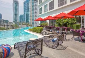 a pool with tables and chairs and red umbrellas at Novotel Rockwell View Hotel Residences in Manila