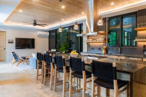 a kitchen with a large bar with chairs around it at NEW Modern 6BR, Pool, Walk 2 Beach, Sleeps 20 in Playa Guiones
