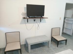 un soggiorno con 2 sedie, un tavolo e una TV di Los Jazmines depto a Cafayate