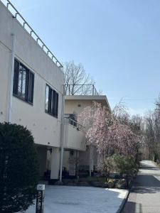 a white building with a flowering tree in front of it at 紅富士苑 in Yamanakako