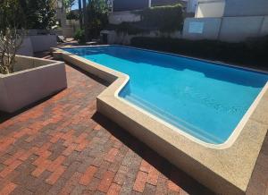 a large swimming pool with a brick floor and a brick at Como Mezzanine Retreat in Perth