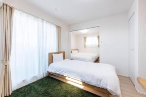 a white bedroom with a bed and a window at Anecis Honjin in Nagoya