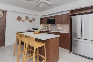 Una cocina con una isla con sillas y un refrigerador. en Brand New Condo near beach, en Santa Cruz Huatulco