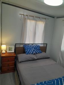 a bedroom with a bed and a window and a nightstand at The Holiday Hut in Lightning Ridge