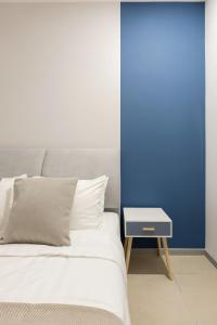 a bed with a side table next to a blue wall at 22 Macalisterz George Town in George Town