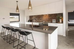 バッセルトンにあるBayside Luxury Escape Busselton with EV chargerのバースツール付きの大きな島のあるキッチンが備わります。