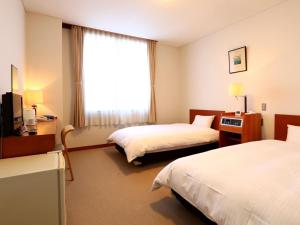 a hotel room with two beds and a window at KANEMITSU CAPITAL HOTEL in Takamatsu