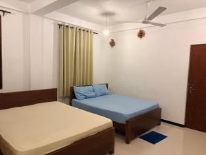 a bedroom with two beds and a ceiling fan at Metro Stay in Kurunegala