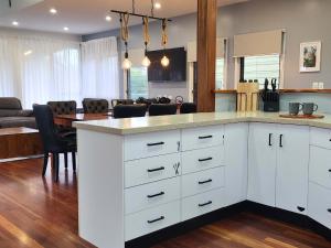 a kitchen with white cabinets and a living room at Bushys Hilltop (Kingfisher Bay, Kgari) in K'gari Island (Fraser Island)