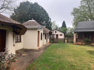 a group of houses with a fence and a yard at Pavlovna Bunk with the kids Cottage in Himeville