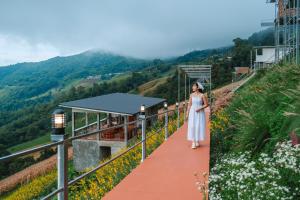 a woman in a white dress standing on a red path at หลงฮักเขา ภูชี้ฟ้า Long Huk Kao Phuchifa in Ban Huai Khu