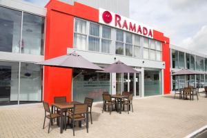een groep tafels en stoelen voor een gebouw bij Ramada Milton Keynes in Milton Keynes